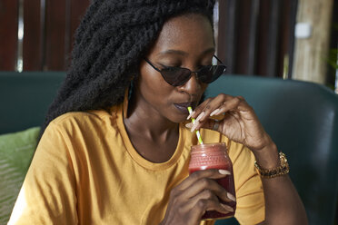 Young woman with dreadlocks drinking a smoothie in a cafe - VEGF00118