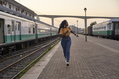 Young woman running on platform at the train station stock photo