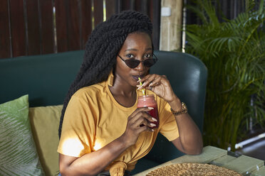 Young woman with dreadlocks drinking a smoothie in a cafe - VEGF00121