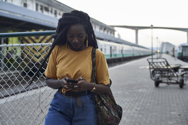 Junge Frau auf dem Bahnsteig des Bahnhofs, die ihr Telefon überprüft - VEGF00134