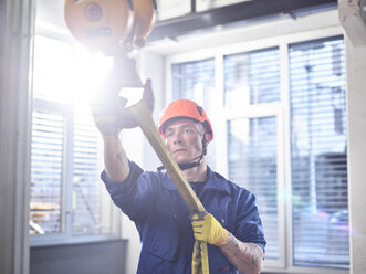 Industriearbeiter beim Befestigen von Hebebändern an einem Hallenkran - CVF01127