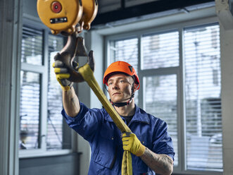 Industriearbeiter beim Befestigen von Hebebändern an einem Hallenkran - CVF01128