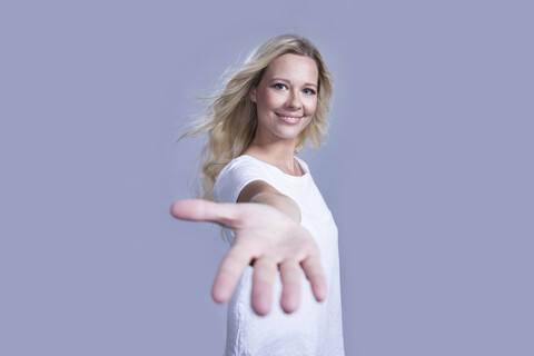 Porträt einer lächelnden blonden Frau, die ihre helfende Hand anbietet, lizenzfreies Stockfoto