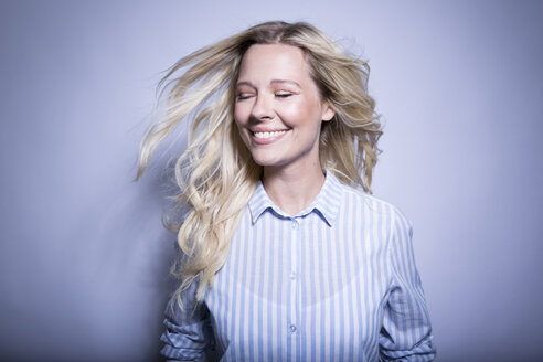 Porträt einer glücklichen blonden Frau, die ihr Haar wirft - MFRF01291