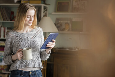 Smiling woman drinking coffee and using digital tablet - BLEF01821