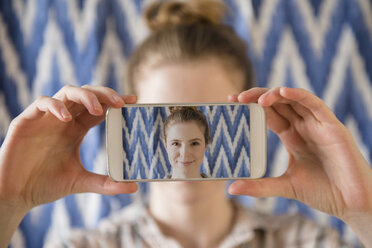 Woman holding photograph of cell phone selfie in front of face - BLEF01838