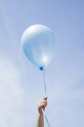Hand eines kaukasischen Mädchens, das einen blauen Luftballon im blauen Himmel hält - BLEF01841