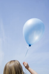Kaukasisches Mädchen hält blauen Luftballon in blauem Himmel - BLEF01842