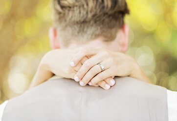 Hände der kaukasischen Braut umarmen Bräutigam im Freien - BLEF01859