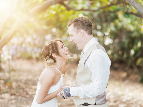 Kaukasische Braut und Bräutigam lachen im Freien, lizenzfreies Stockfoto