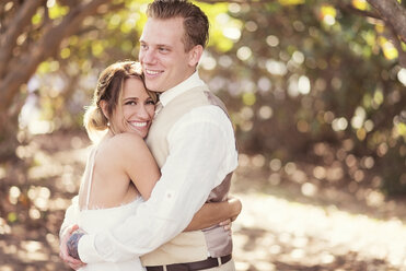 Caucasian bride and groom hugging outdoors - BLEF01861