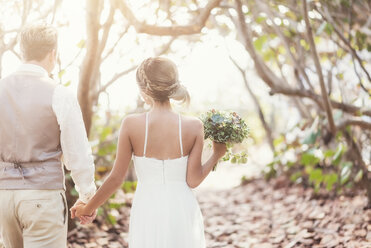 Caucasian bride and groom holding hands outdoors - BLEF01863