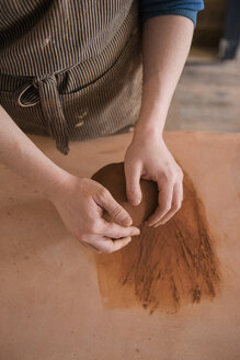 Hands of Caucasian woman rolling pottery clay - BLEF01864