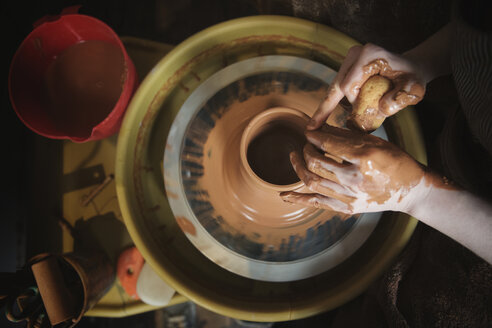 Hands of Caucasian woman shaping pottery clay on wheel - BLEF01868