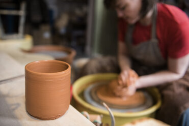 Cup near Caucasian woman shaping pottery clay on wheel - BLEF01871