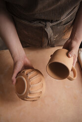 Hand einer kaukasischen Frau, die eine Tasse und eine Schale aus Keramik hält - BLEF01879