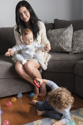 Caucasian mother sitting on sofa playing with sons - BLEF01910