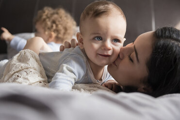 Kaukasische Mutter liegt auf dem Bett und küsst ihren kleinen Sohn - BLEF01922