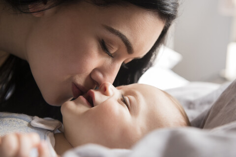 Nahaufnahme einer kaukasischen Mutter, die ihren kleinen Sohn küsst, lizenzfreies Stockfoto