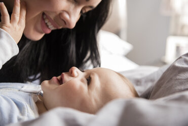 Close up of Caucasian mother laying on bed with baby son - BLEF01929