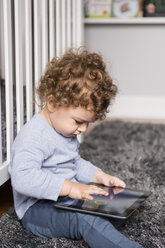 Kaukasischer Junge sitzt auf dem Boden und spielt mit einem digitalen Tablet - BLEF01931
