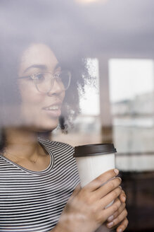 Nachdenkliche afroamerikanische Frau trinkt Kaffee hinter einem Fenster - BLEF01940