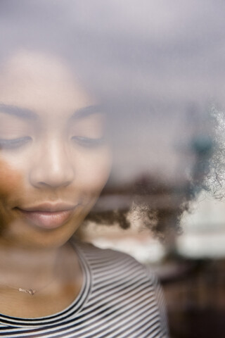 Nachdenkliche afroamerikanische Frau hinter dem Fenster, lizenzfreies Stockfoto