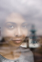 Lächelnde afroamerikanische Frau hinter dem Fenster - BLEF01942