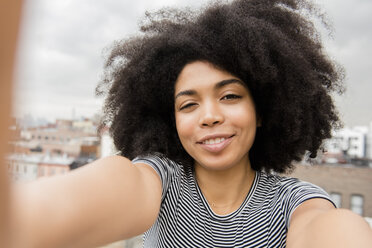 Lächelnde afroamerikanische Frau posiert für ein Selfie auf dem Dach - BLEF01945