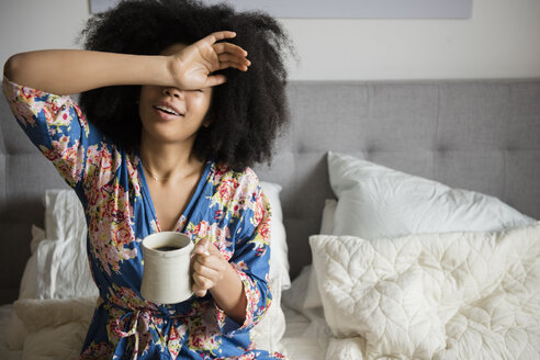 Afroamerikanische Frau sitzt im Bett und trinkt Kaffee - BLEF01948
