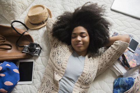 Afroamerikanische Frau, die auf dem Bett liegt und sich auf die Reise freut, lizenzfreies Stockfoto