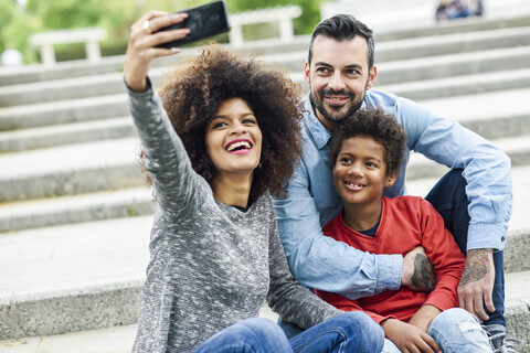 Glückliche Familie macht Selfies in einem Park, lizenzfreies Stockfoto