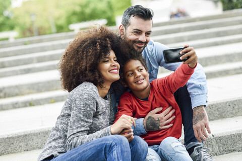 Glückliche Familie macht Selfies in einem Park, lizenzfreies Stockfoto