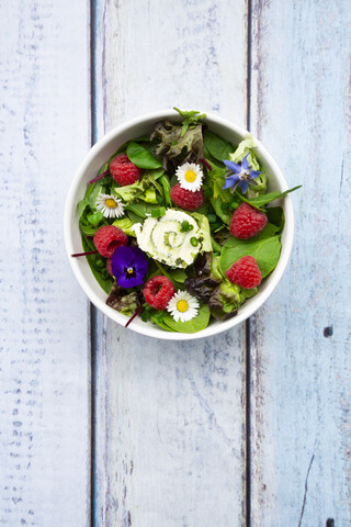 Schüssel mit Blattsalat mit Himbeeren und Frischkäse, garniert mit essbaren Blüten, lizenzfreies Stockfoto