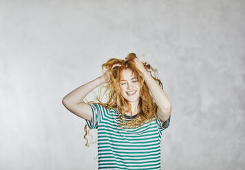 Portrait of redheaded young woman with hands in hair - FMKF05661