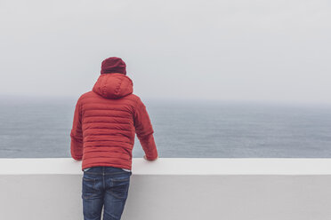 Portugal, Algarve, Sagres, Cabo de Sao Vicente, Rückansicht eines Mannes mit roter Mütze und Jacke, der auf das Meer schaut - MMAF00885