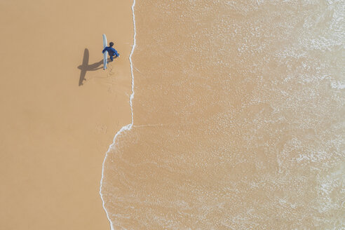 Portugal, Algarve, Sagres, Praia da Mareta, aerial view of man carrying surfboard on the beach - MMAF00900