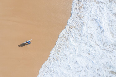Portugal, Algarve, Sagres, Praia da Mareta, aerial view of man carrying surfboard on the beach - MMAF00901