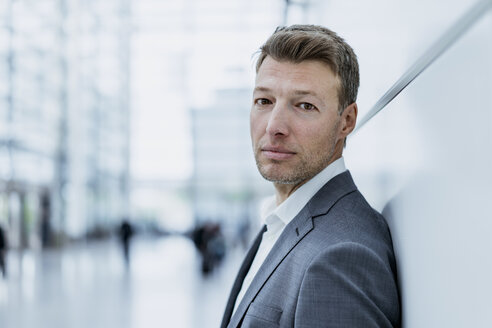 Portrait of businessman leaning against a wall - DIGF06825