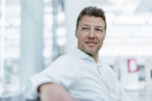 Businessman sitting in waiting area looking around - DIGF06833