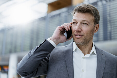 Porträt eines Geschäftsmannes am Handy auf dem Flughafen, lizenzfreies Stockfoto