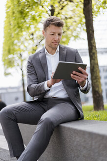 Businessman using tablet outside in the city - DIGF06843