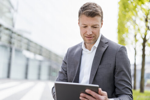 Businessman using tablet outside in the city - DIGF06845