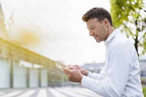 Businessman using tablet outside in the city - DIGF06849