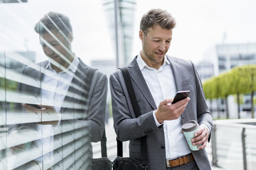 Geschäftsmann mit Mobiltelefon und Kaffee zum Mitnehmen in der Stadt - DIGF06861