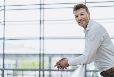 Portrait of smiling businessman leaning on railing - DIGF06870