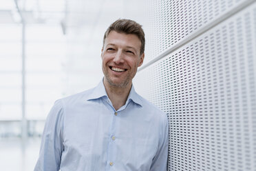 Portrait of happy businessman leaning against a wall - DIGF06875