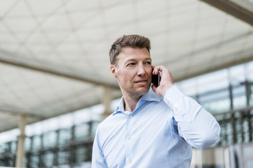 Businessman outside in the city on cell phone looking around - DIGF06882