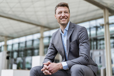 Smiling businessman sitting outside in the city - DIGF06885