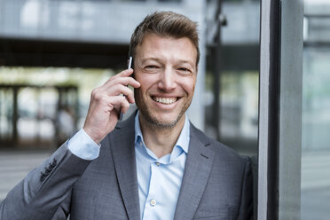 Portrait of happy businessman on cell phone outdoors - DIGF06890